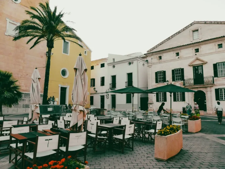 Abogado de derecho administrativo en Menorca: plaza tranquila de Menorca con terrazas y arquitectura tradicional