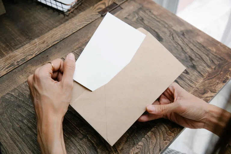 Manos sacando una carta de un sobre sobre una mesa de madera
