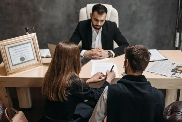 Abogado revisando documentos con dos clientes en un despacho