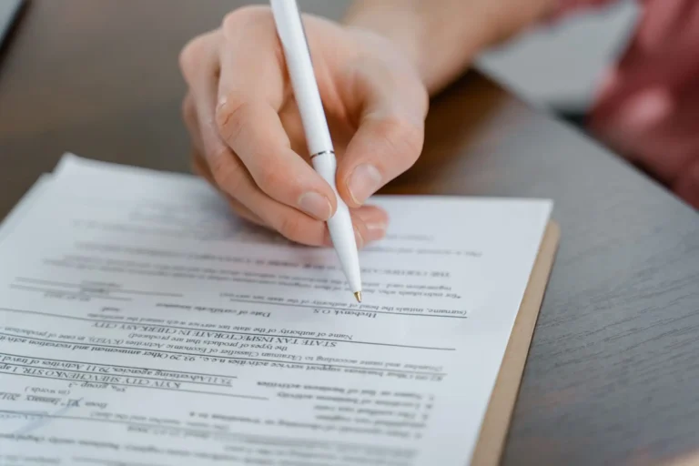 Mano con un bolígrafo rellenando un documento