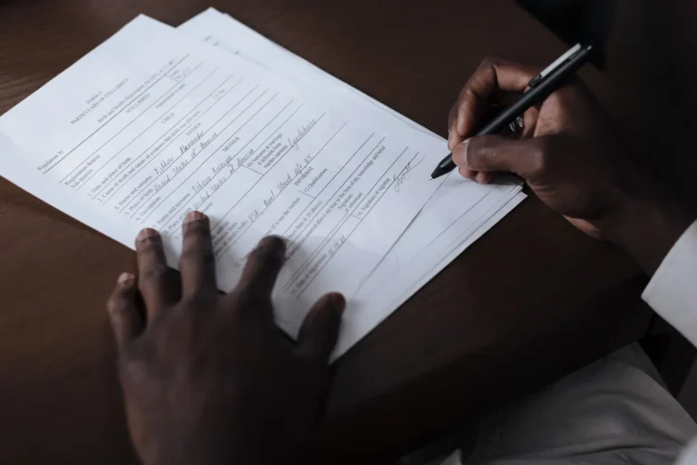 Hombre firmando documentos oficiales sobre una mesa