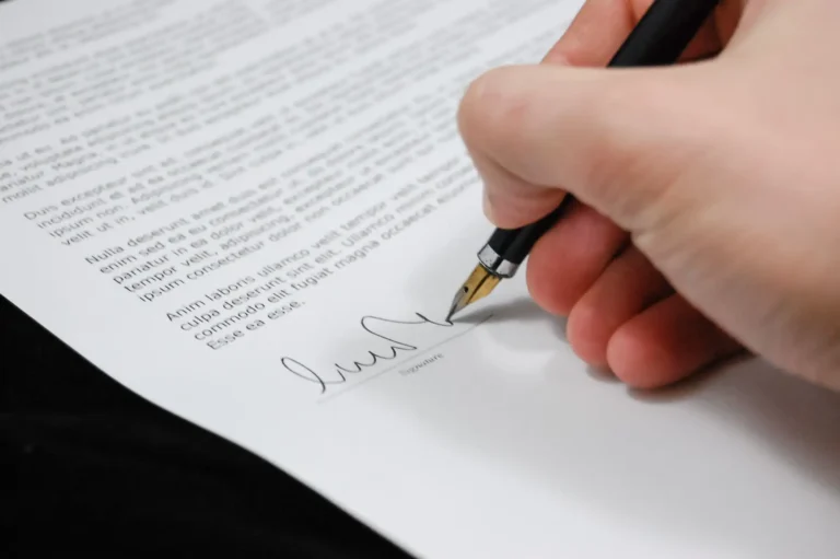 Mano firmando un documento con una pluma estilográfica
