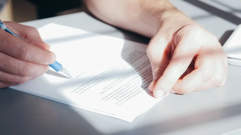 Manos firmando un contrato con un bolígrafo azul