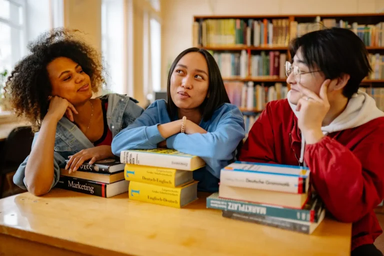 Tres estudiantes estudiando juntos en una biblioteca