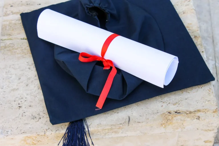 Birrete de graduación con un diploma atado con cinta roja