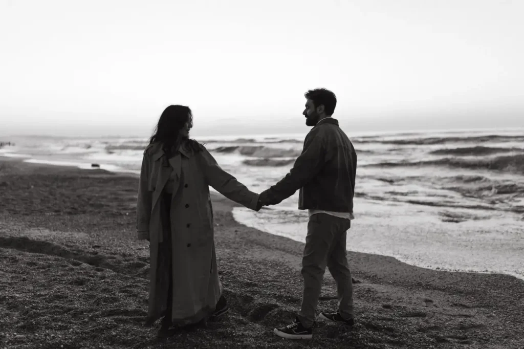 Pareja de la mano en la playa al atardecer