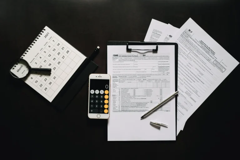 Calculadora, móvil y formularios sobre una mesa oscura