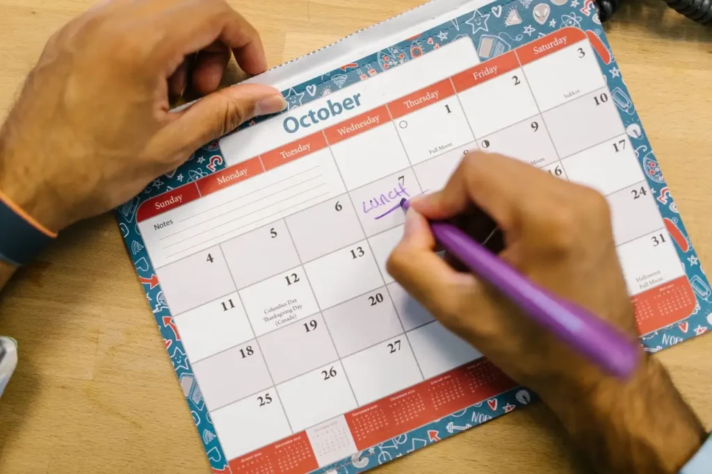 Persona anotando fechas en un calendario sobre la mesa