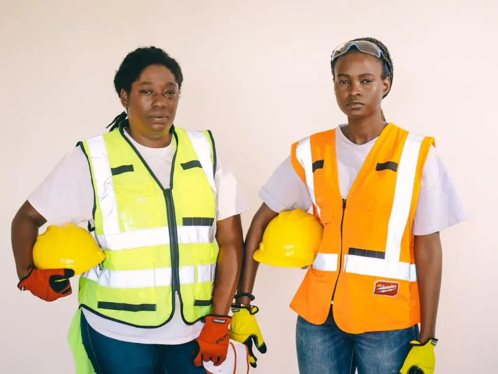 Dos trabajadoras de la construcción con chaleco reflectante y casco