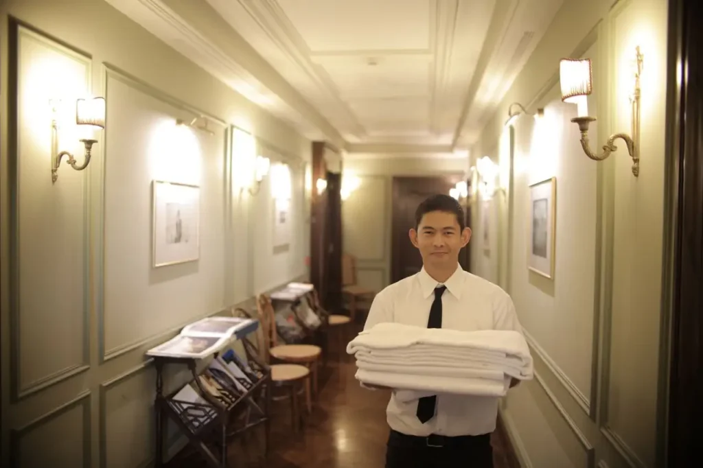 Empleado de hotel llevando toallas por un pasillo