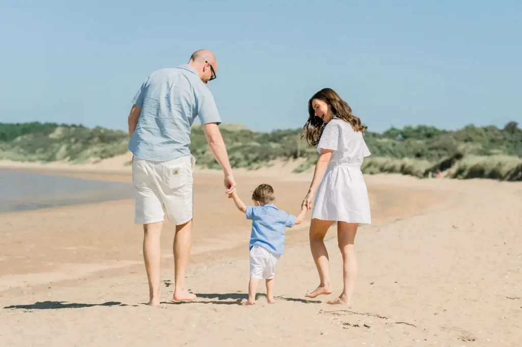 Padre y madre paseando de la mano con su hijo por la playa