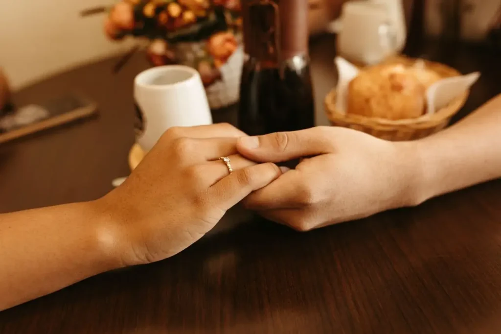Pareja cogida de la mano en la mesa de una cafetería