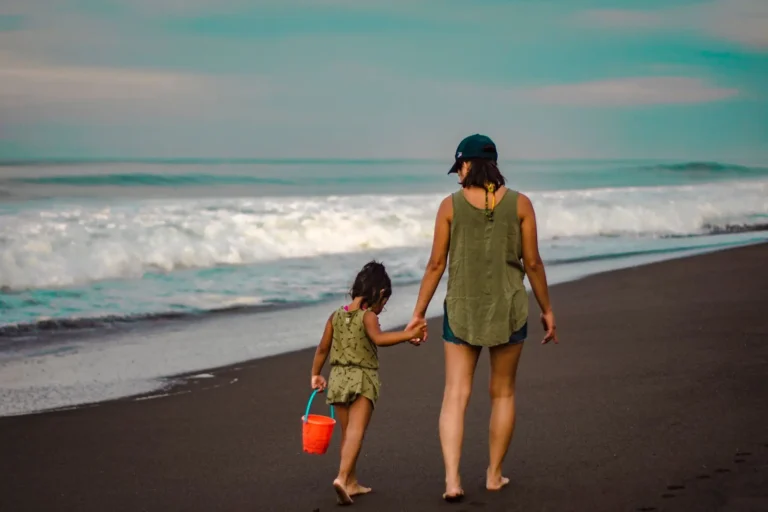Arraigo familiar: madre e hija paseando de la mano por la orilla del mar