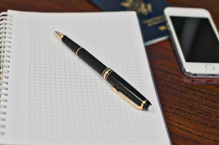 Libreta, bolígrafo, móvil y pasaporte sobre un escritorio