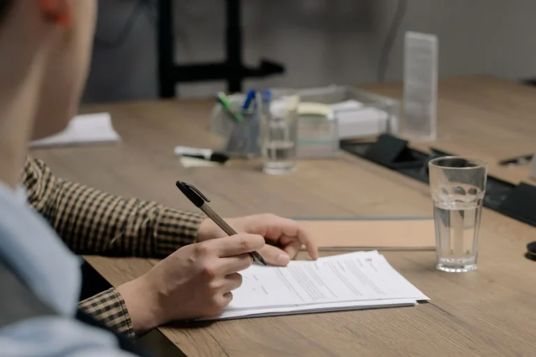 Arraigo sociolaboral: persona firmando un contrato en una mesa de madera