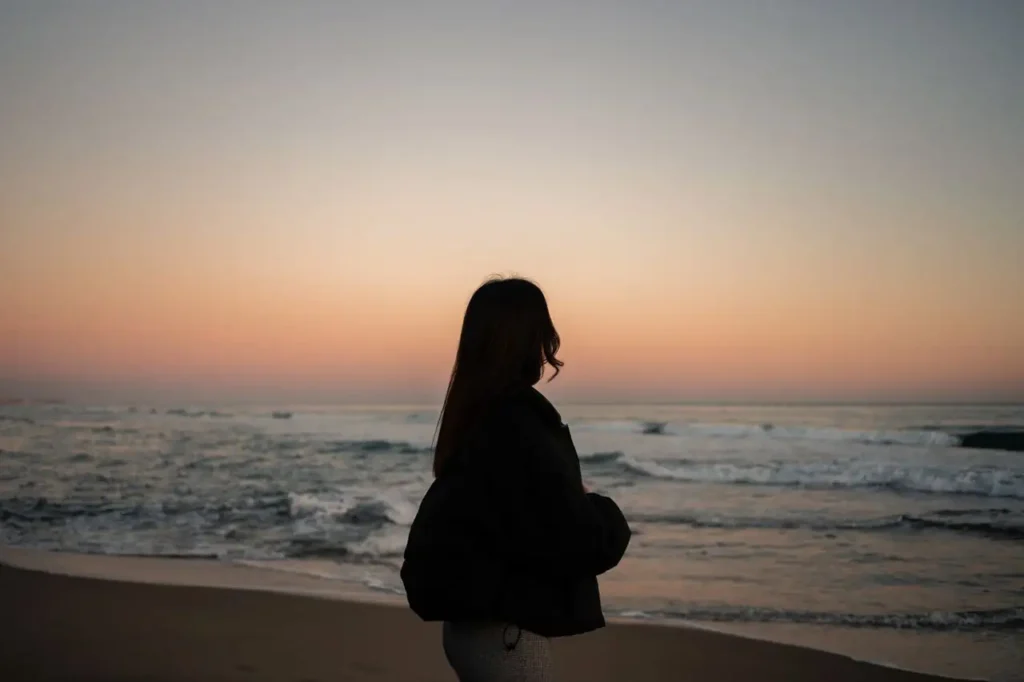 Silueta de una mujer frente al mar al atardecer