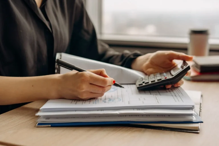 Reclamar salarios: persona usando una calculadora con documentos económicos