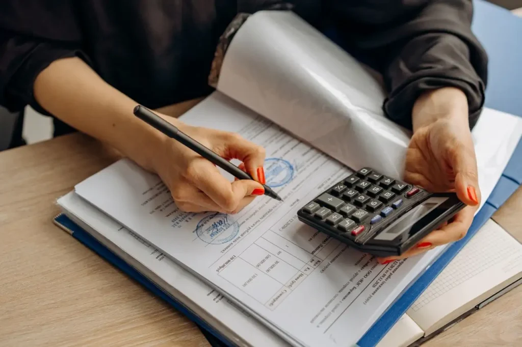 Persona revisando documentos con una calculadora